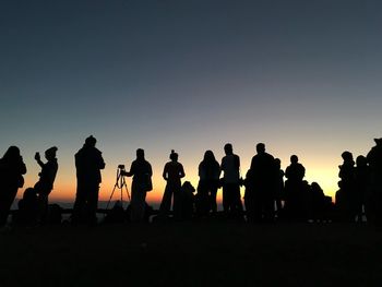 Silhouette people standing against clear sky during sunset