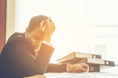 Frustrated businessman sitting with documents at table in office