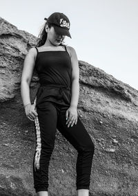 Young woman standing on rock against sky