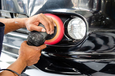 Cropped hands of man polishing car