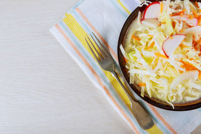 High angle view of salad in bowl with fork on table