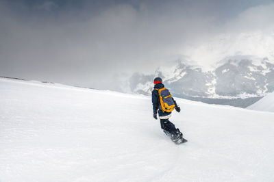 Young sportswoman snowboarder ride on a snowy slope against the backdrop of mountains on a winter