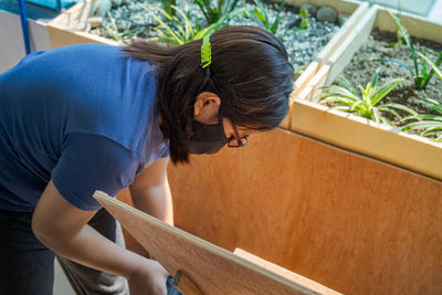 A young girl wearing face mask doing woodworking project.