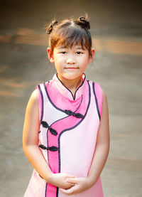 Portrait of cute girl standing against pink background