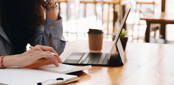 Midsection of woman working with laptop on table