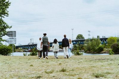 Full length rear view of young friends walking towards river