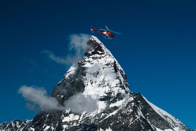 Low angle view of snowcapped mountains against blue sky