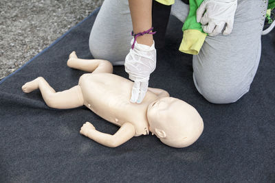 Midsection of paramedics performing cpr on baby mannequin