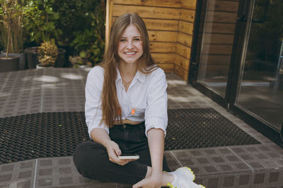 Portrait of young woman standing against wall