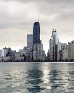 Sea by cityscape against sky