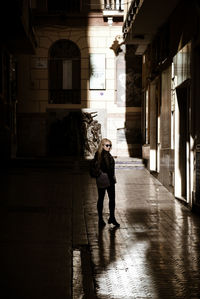 Full length of man standing on footpath amidst buildings