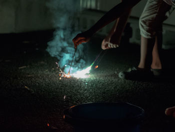 Low section of man burning sparklers on street