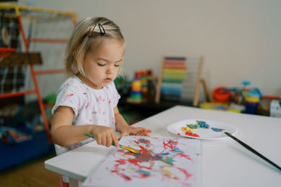 Cute girl drawing on paper at home