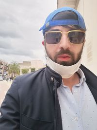 Portrait of young man wearing sunglasses against sky