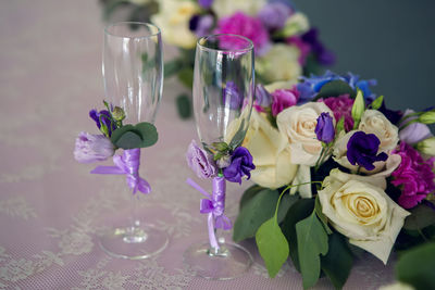 Arrangement of different flowers is on the table with glasses of the newlyweds, wedding
