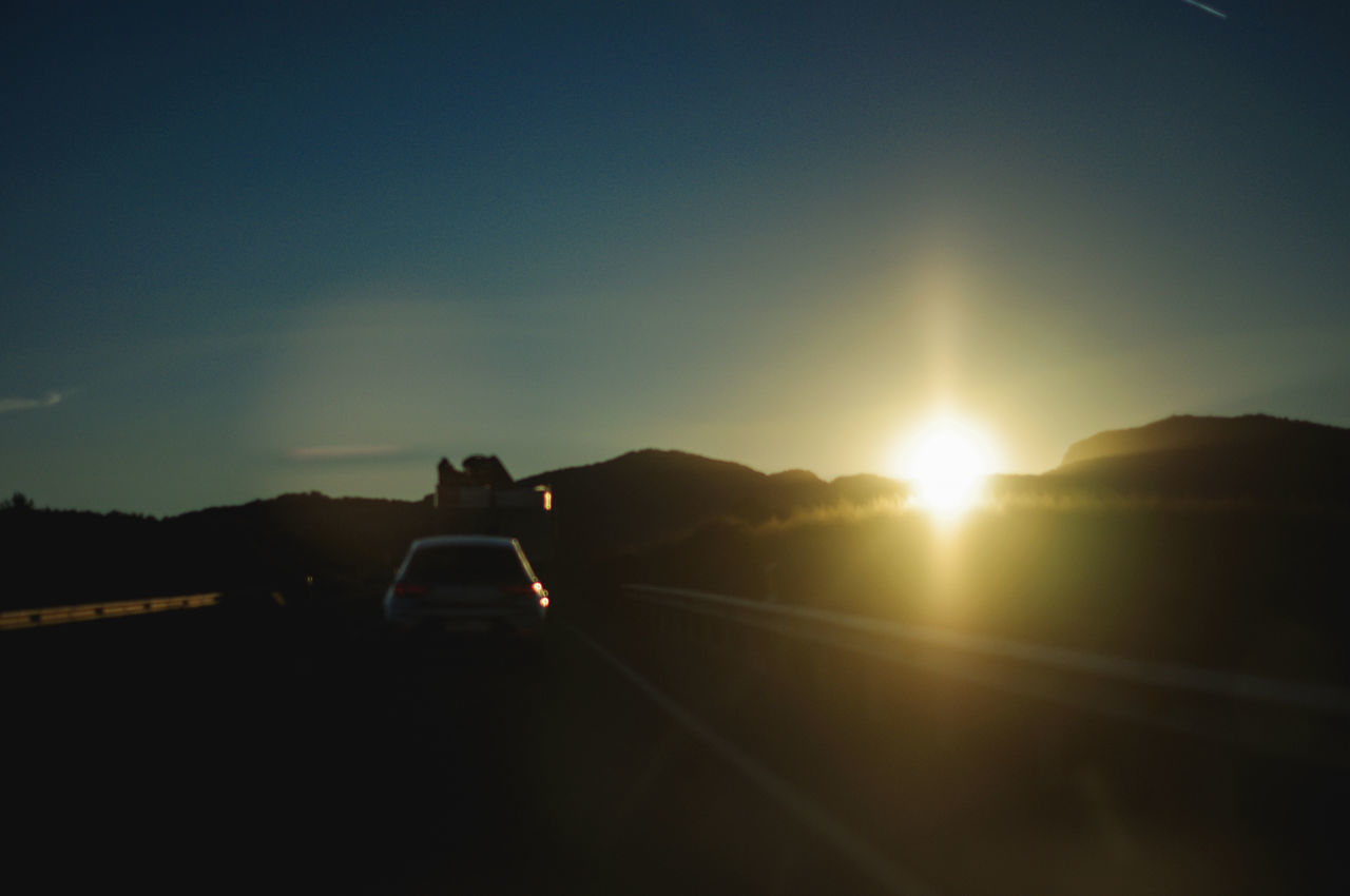 CAR ON ROAD AT SUNSET