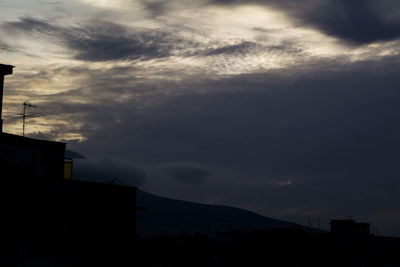 Low angle view of silhouette buildings against cloudy sky