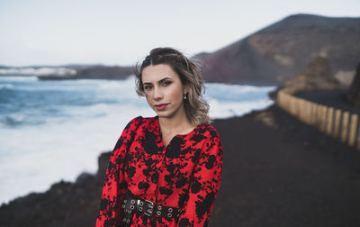 Portrait of beautiful young woman standing against sky