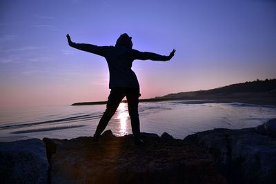 Rear view of man standing on rock at beach