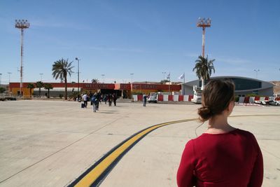 Rear view of people walking in city against sky