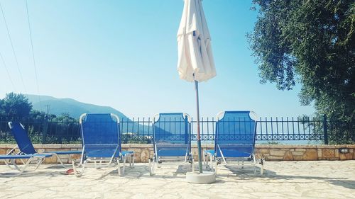 Chairs on beach against clear blue sky