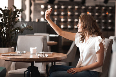 Smiling woman taking selfie at cafe