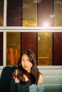 Portrait of young woman looking through window