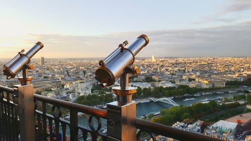 Coin-operated binoculars overlooking cityscape against sky