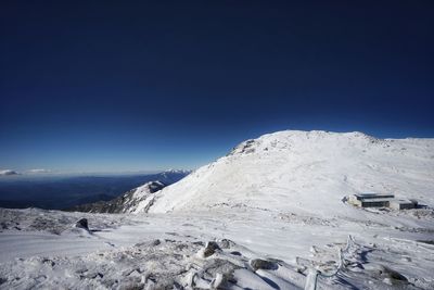 Scenic view of snowcapped mountains against clear blue sky