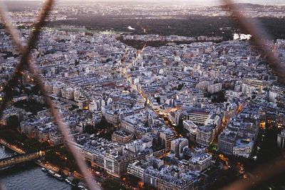 High angle view of cityscape seen through fence during sunset