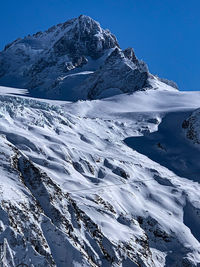 Scenic view of snowcapped mountains against blue sky