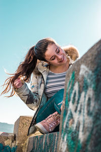 Young woman smiling while standing against clear sky