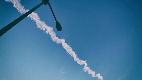 Low angle view of vapor trails against blue sky