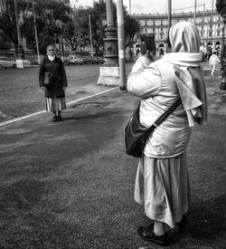 Rear view of people walking on street in city