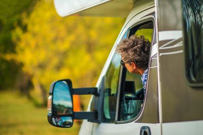 Woman peeking out from window of truck by side-view mirror