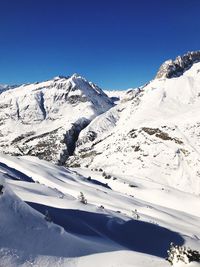 Scenic view of snowcapped mountains against clear blue sky