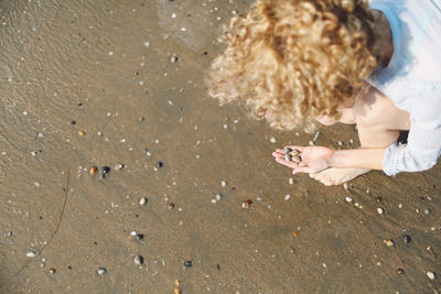 High angle view of woman collecting pebbles at beach