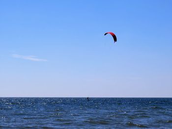 Kite flying over sea against blue sky