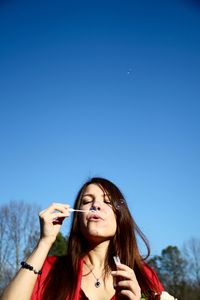 Low angle view of beautiful woman against blue sky