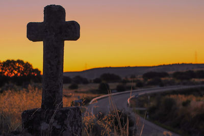 Cross on cemetery against sky during sunset