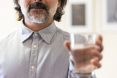 Happy man holding glass of water inside