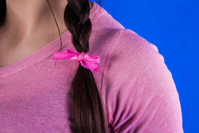 Midsection of woman with braided hair against blue background