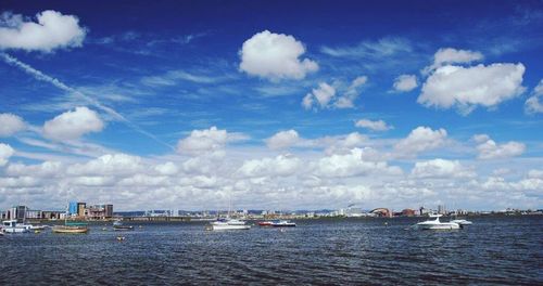 Boats in sea against cloudy sky