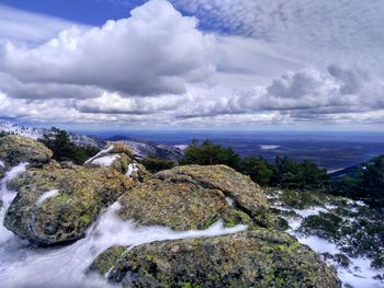 Scenic view of rocks with snow over horizon with lake against sky