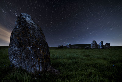 Rocks on field against sky at night