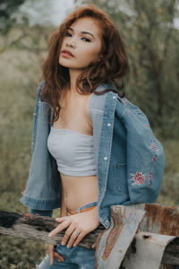 Beautiful young woman standing against tree