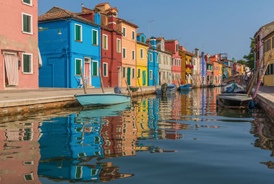 Boats moored in canal amidst buildings against sky