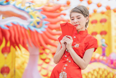 Midsection of woman holding red while standing outdoors