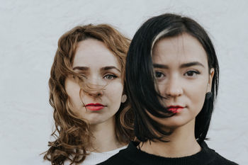 Portrait of lesbian couple standing against white wall
