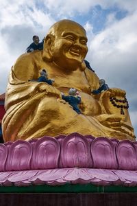 Low angle view of statue of buddha against cloudy sky